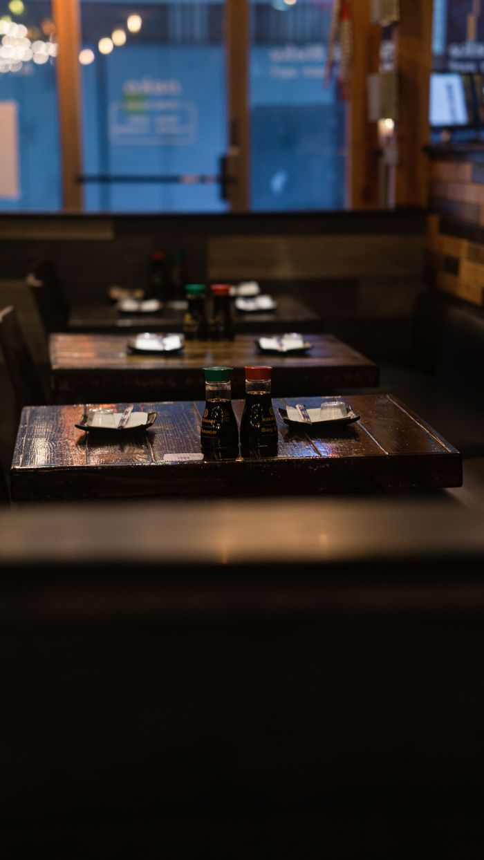 Warm and inviting restaurant interior featuring wooden tables set with condiments and plates.