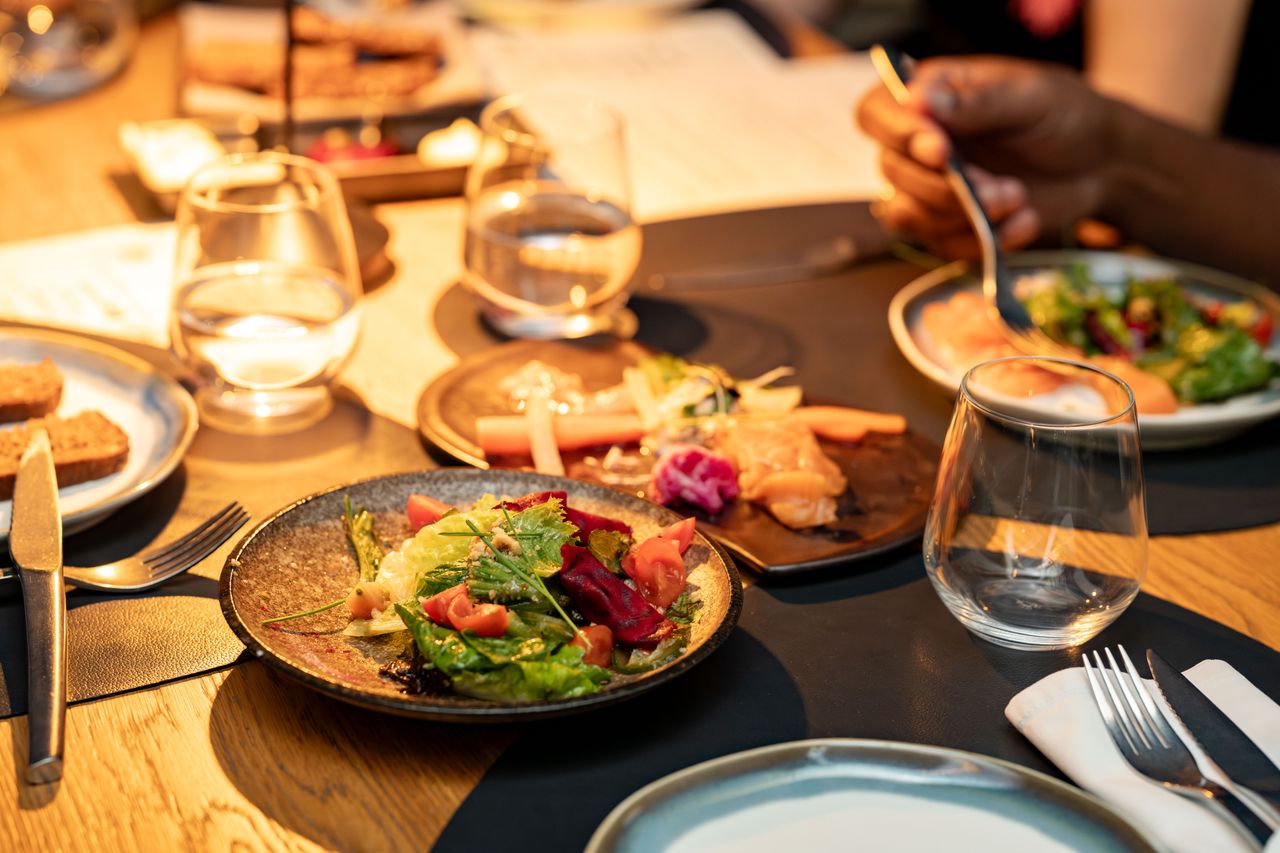 A beautifully set dinner table with gourmet salads and glassware, ideal for a classy dining experience.